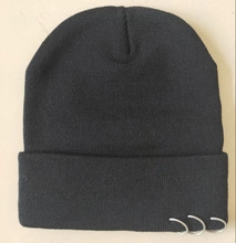 Detailed knit texture of a black beanie featuring three decorative silver metal rings