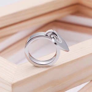 Modern silver stainless steel heart ring with sparkling crystals on a wooden stand