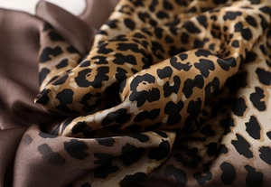 Macro shot of high-quality leopard print silk satin fabric with elegant drape and luster