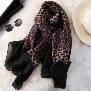 Elegant gradient leopard print scarf with black sheer panel on white plush carpet