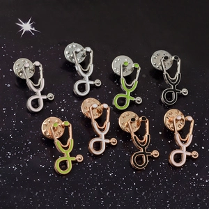 Vintage metal stethoscope brooches in assorted colors on a black background