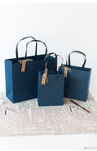 Three sizes of dark blue paper gift bags with black handles and vintage Thank You tags