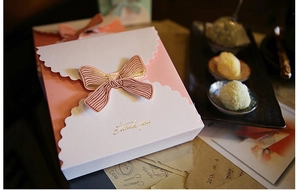 Détail de boîte cadeau avec nœud rose, texte doré Thank You et bords ondulés