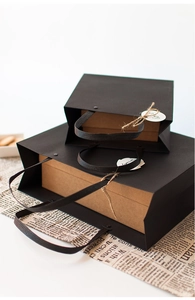 Detail of black gift bags with rivet handles and small Especially FOR labels on top