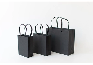 Detailed view of black minimalist paper gift bags with sturdy rope handles in three sizes