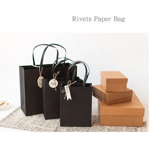 Three sizes of premium black paper gift bags with handles and rivets shown on a desk