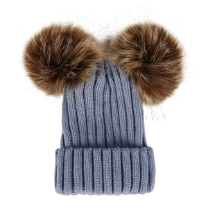 Close-up of baby knit hat in dusty blue with two fluffy brown faux fur pom-poms