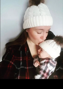 Matching white cable knit hats for mother and baby with fluffy faux fur pom poms