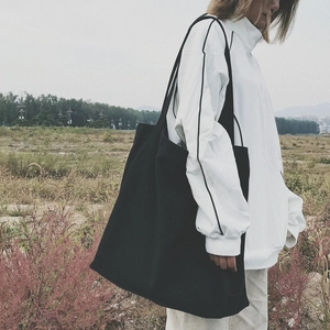 Minimalist black canvas tote bag for women with large capacity shown in an outdoor setting