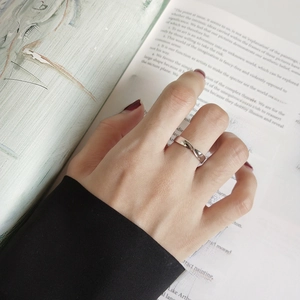 Minimalist 925 sterling silver Mobius twist ring worn against a vintage book background