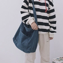 Détail du grand sac cabas en denim bleu avec poche avant montrant la texture du tissu