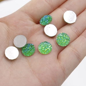 Close-up of 10mm green glitter resin druzy cabochons on a hand for DIY jewelry making