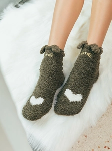 Detail of plush brown cat socks with soft 3D ears and white heart pattern on a furry rug