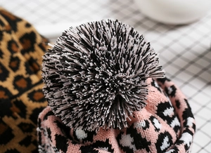 Close-up of leopard print knit hat featuring a large fluffy faux fur pompom detail
