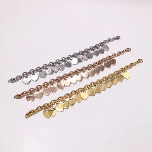 Detailed view of chunky chain bracelets with heart charms in gold, rose gold and silver