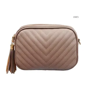 Ashen faux leather crossbody bag with V-quilted stitching, tassel detail and gold chain