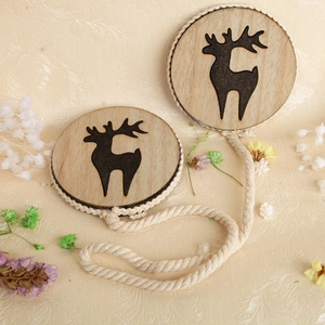 Macro detail of wooden magnetic curtain tieback with deer cutout and braided cotton rope