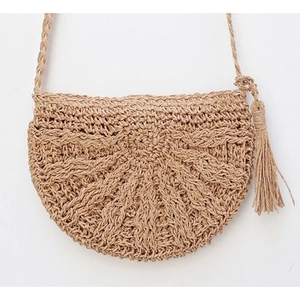 Close-up of semi-circular straw crossbody bag with natural woven texture and long tassel