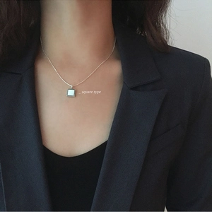 Detail of square silver pendant with mother of pearl inlay on model's neckline