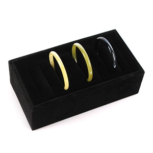 Premium black velvet jewelry display tray with slots showing three elegant bracelets