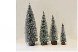 Detailed view of four mini snow-flocked Christmas trees with natural wood bases