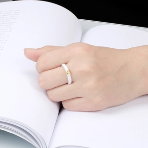Minimalist white ceramic ring with gold star and diamond detail worn on a finger