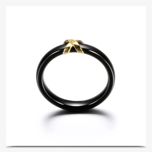 Macro detail of black ceramic ring featuring a golden X-shaped crossover diamond design