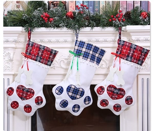 Close-up of paw-shaped plaid Christmas stockings with bone tags on a festive fireplace