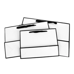Minimalist white paper gift bags with black ribbon handles in three various sizes