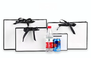 White gift bags with black bow handles in four sizes compared to standard beverage bottles