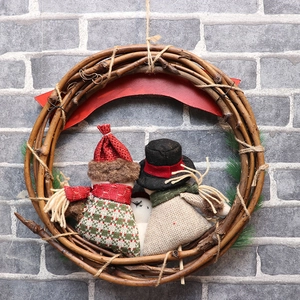 Christmas rattan wreath with two plush dolls in red and green plaid outfits on a brick wall