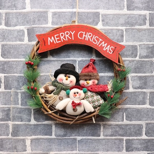 Handcrafted Christmas wreath with three plush snowmen and pine needles on rattan