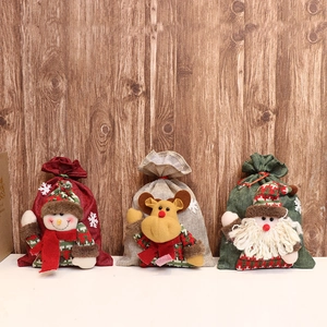 Three Christmas burlap gift bags featuring snowman, elk, and Santa Claus characters