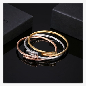 Detailed macro shot of 18K gold-plated stainless steel cable wire twist bangles in three colors