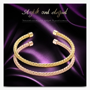 Detail of gold and rose gold twisted cable open bracelets on a purple silk fabric