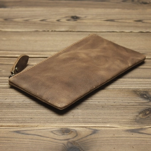 Close-up of a vintage brown crazy horse leather long wallet on a rustic wooden table