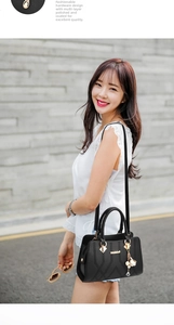 Detail of black pebbled leather tote with V-shaped stitching and gold hardware with charms