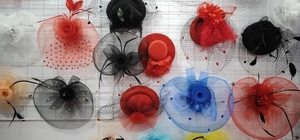Multiple colors of feather mesh fascinator hats displayed on a grid wall for party