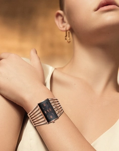 Close-up of a rose gold hollow cuff watch with a sleek black rectangular dial on a wrist