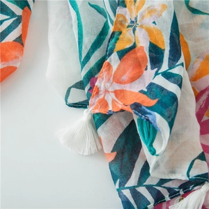 Detail of tropical floral print on breathable scarf with white and teal tassels