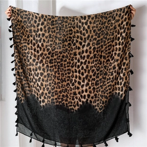 Detail of leopard print scarf featuring black gradient hem and soft tassel fringe
