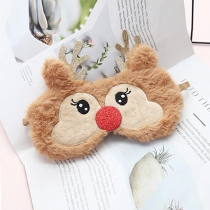 Cute plush reindeer sleep mask with gold antlers and red sequin nose on a magazine background
