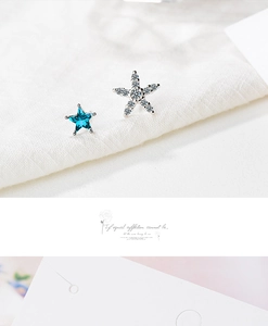 Close-up of asymmetric star earrings featuring blue gemstone and white crystal details