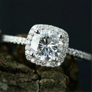 Macro shot of silver zircon ring with cushion halo and pave band on natural wood