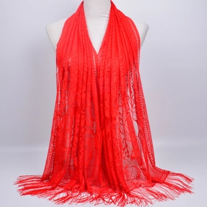 Detailed view of red lace shawl with elegant floral hollow patterns and long fringe tassels