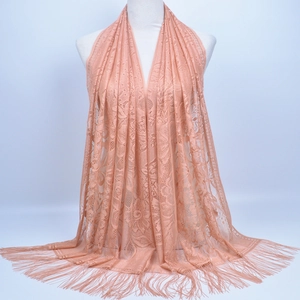 Detail of peach pink lace shawl featuring floral hollow-out patterns and fine fringe tassels