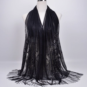 Detail view of black lace shawl featuring intricate floral hollow patterns and fringe trim