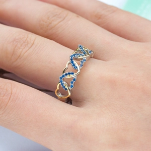 Detail of two-tone heart ring in gold and silver with blue cubic zirconia stones