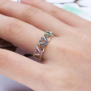 Detailed view of entwined gold and silver heart ring with multi-colored crystals