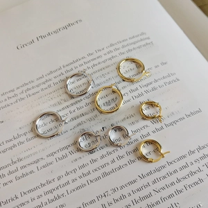 Classic silver and gold hoop earrings in various sizes on an open book page
